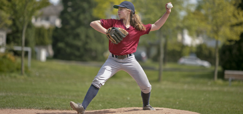 Young woman pitcher winding up to throw