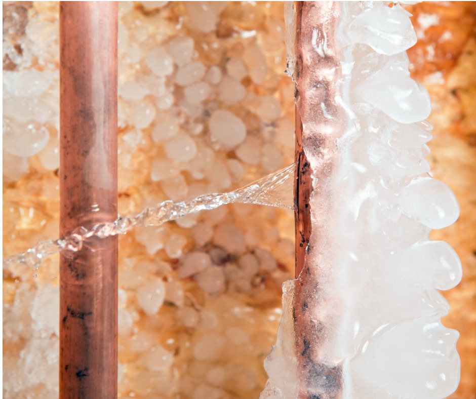 Photo of an ice-covered, burst copper pipe spraying water inside the walls