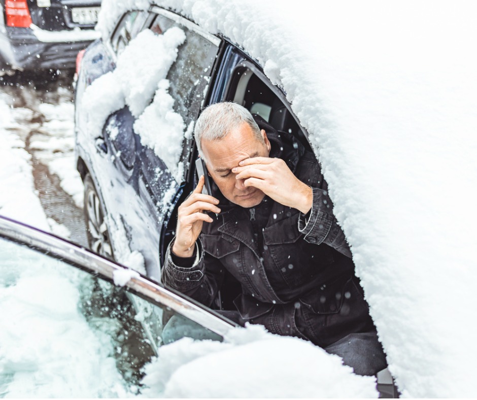 Photo of a man stuck in a snow-covered car