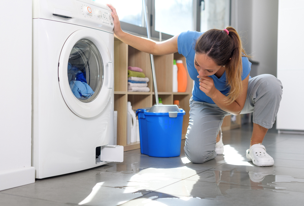 Photo of a woman looking at a washing machine overflow
