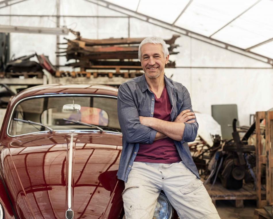 Man leaning against a vintage car and smiling
