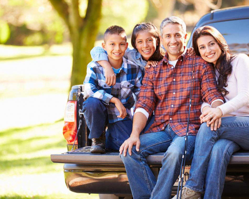 Family of four sitting on a pickup truck's tailgate.
