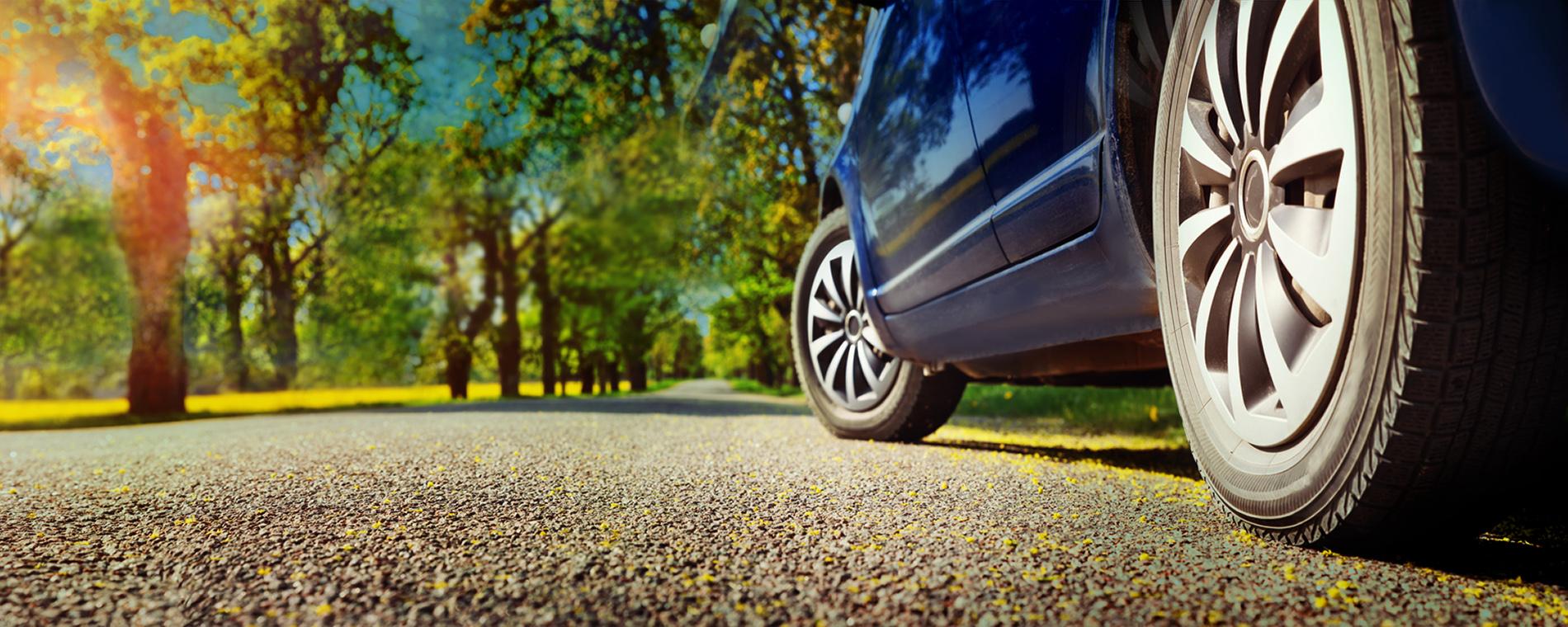 Photo of a blue car driving on a sunny day
